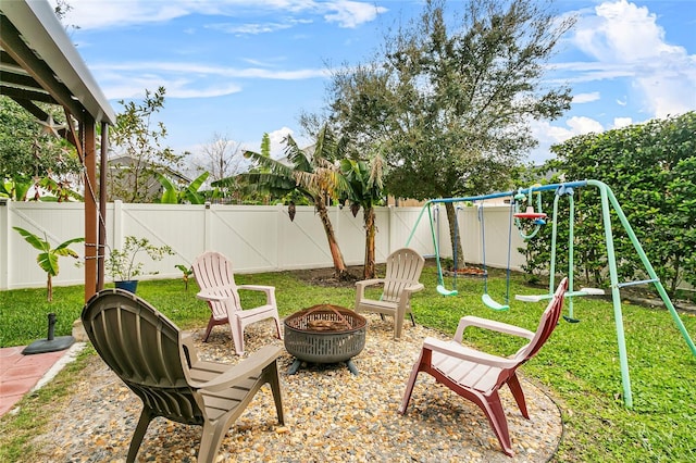 view of yard with a fenced backyard, a fire pit, and a playground