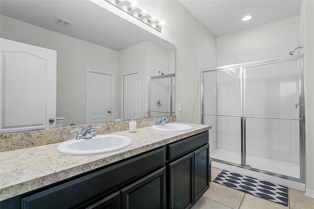 full bath with double vanity, a stall shower, tile patterned flooring, and a sink