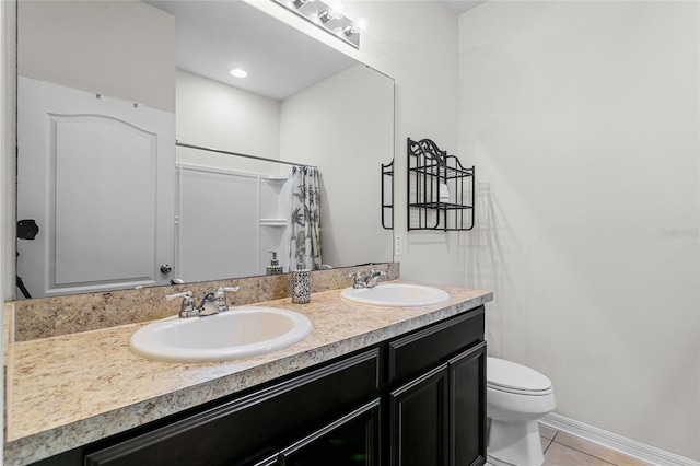 full bath with toilet, double vanity, a sink, and tile patterned floors