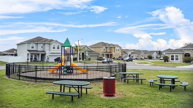 communal playground featuring a residential view, fence, and a lawn