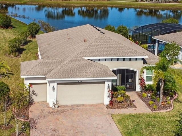 view of front of home with a water view, glass enclosure, decorative driveway, and stucco siding