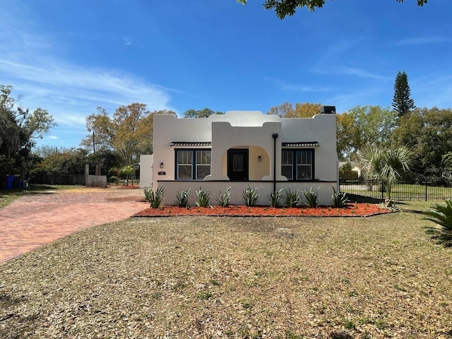 southwest-style home featuring fence, a front lawn, and stucco siding