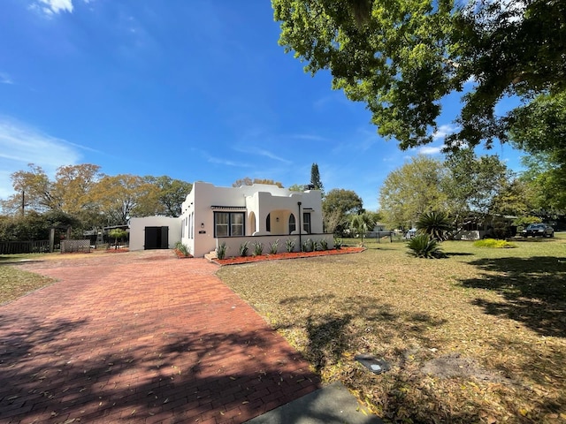 view of front of home with fence, a front lawn, and stucco siding