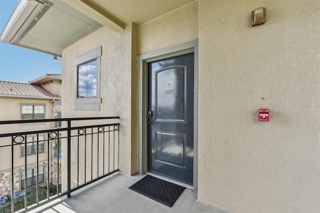 property entrance with a balcony and stucco siding