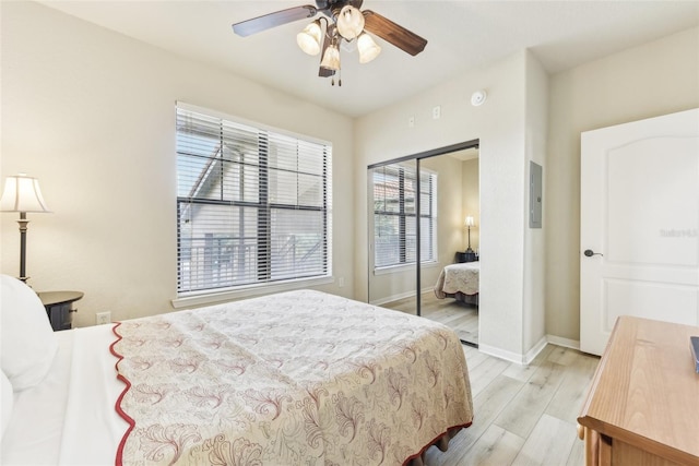 bedroom featuring a ceiling fan, light wood-style flooring, baseboards, and a closet