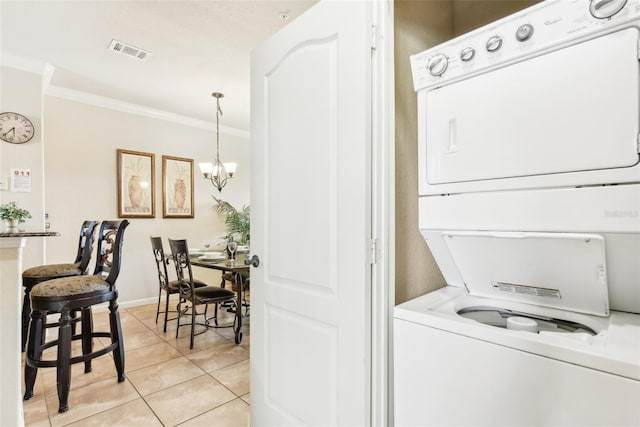 laundry area featuring light tile patterned floors, laundry area, visible vents, crown molding, and stacked washing maching and dryer