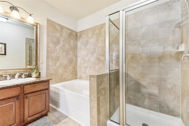 full bathroom featuring a stall shower, tile patterned flooring, a garden tub, and vanity