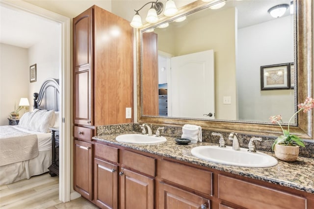 bathroom with double vanity, connected bathroom, a sink, and wood finished floors