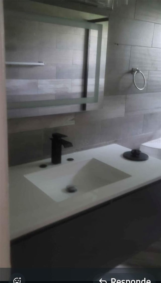 bathroom featuring a sink and decorative backsplash