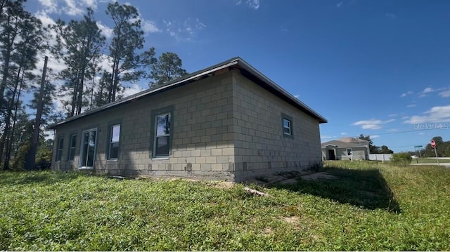 view of property exterior featuring concrete block siding and a yard