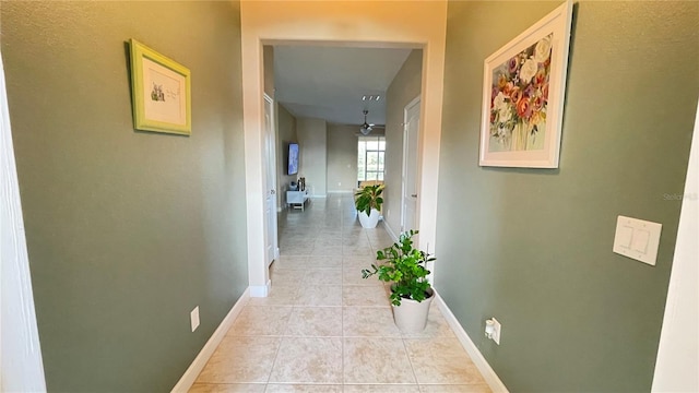 corridor featuring baseboards and light tile patterned floors