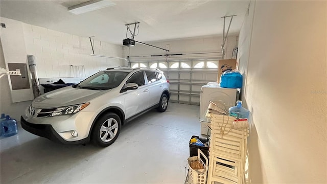 garage featuring electric panel, washer / clothes dryer, and a garage door opener