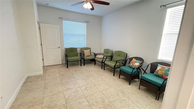 living area featuring light tile patterned floors, ceiling fan, and baseboards