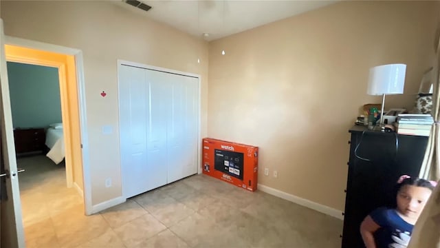 bedroom featuring a closet, light tile patterned flooring, and baseboards