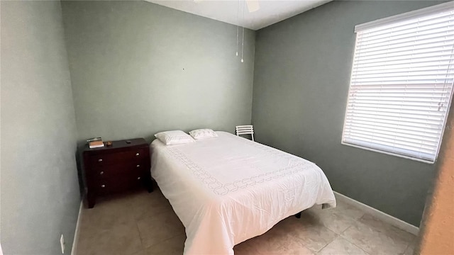 bedroom featuring multiple windows, baseboards, a ceiling fan, and light tile patterned flooring