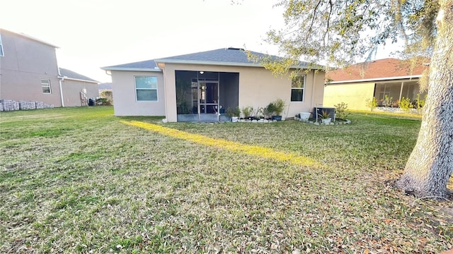 rear view of property with a lawn, a sunroom, and stucco siding