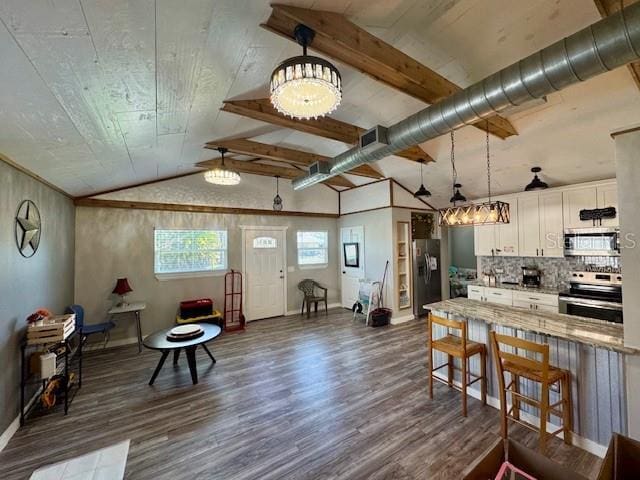 kitchen with dark wood-style floors, stainless steel appliances, white cabinets, vaulted ceiling, and light stone countertops