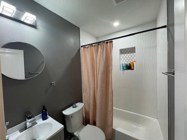 bathroom featuring toilet, shower / tub combo, and vanity