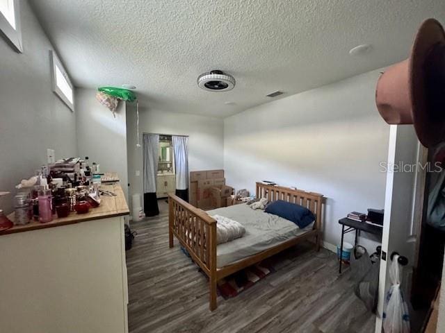 bedroom featuring visible vents, dark wood finished floors, and a textured ceiling