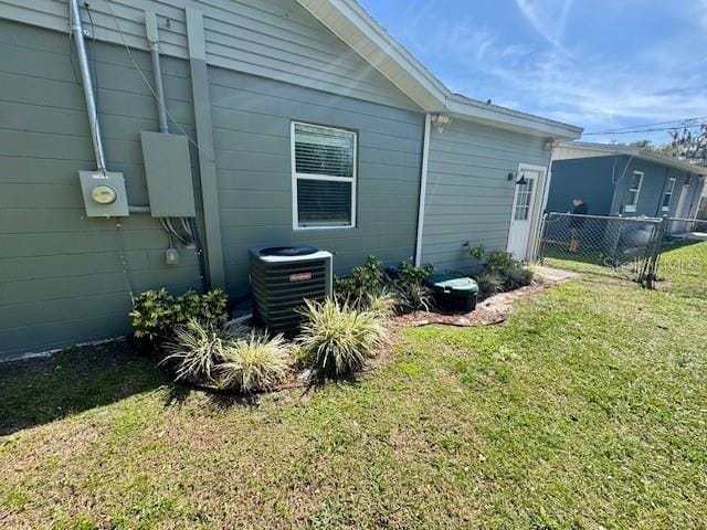 view of side of property featuring cooling unit, fence, and a lawn