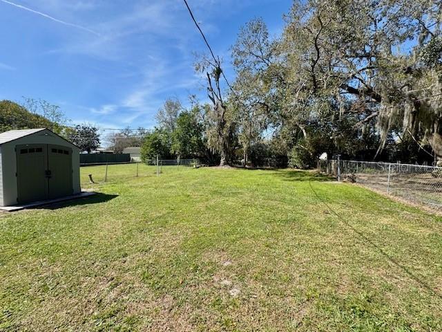 view of yard with an outbuilding, a fenced backyard, and a shed