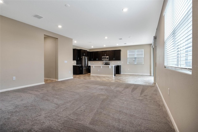 unfurnished living room featuring light carpet, baseboards, and visible vents