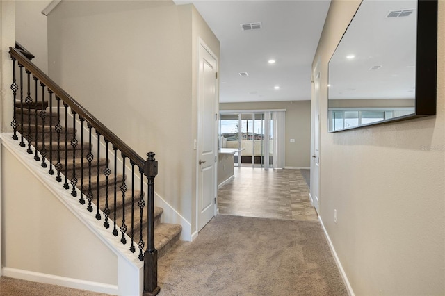 stairs with carpet, visible vents, and baseboards