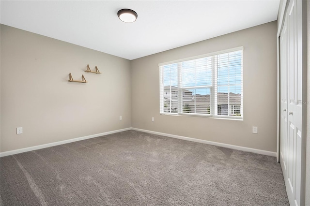 empty room featuring baseboards and carpet flooring