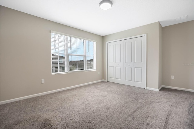 unfurnished bedroom with carpet floors, a closet, visible vents, and baseboards