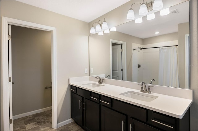 full bathroom featuring double vanity, baseboards, a tile shower, and a sink