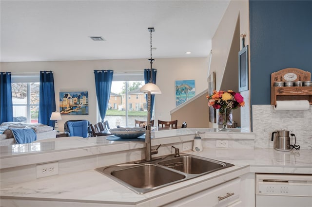 kitchen featuring a wealth of natural light, backsplash, light countertops, and dishwasher