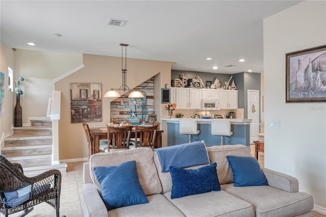 living area with light tile patterned floors, visible vents, baseboards, stairway, and recessed lighting