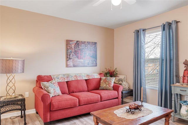 living room with light wood-type flooring, a ceiling fan, and baseboards