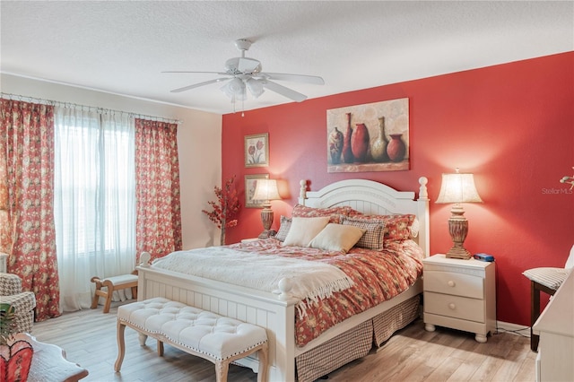 bedroom with a textured ceiling, wood finished floors, and a ceiling fan