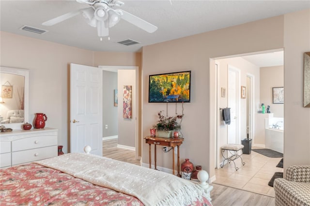 bedroom with ceiling fan, light wood-type flooring, visible vents, and ensuite bathroom