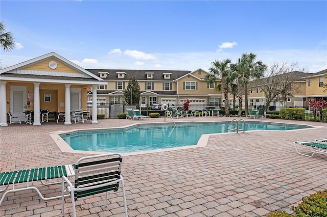 community pool featuring a patio area, fence, and a residential view