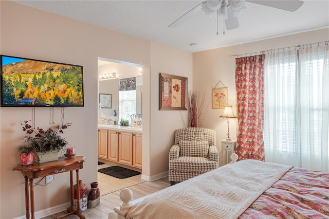 bedroom featuring light wood-style floors, multiple windows, connected bathroom, and a textured ceiling