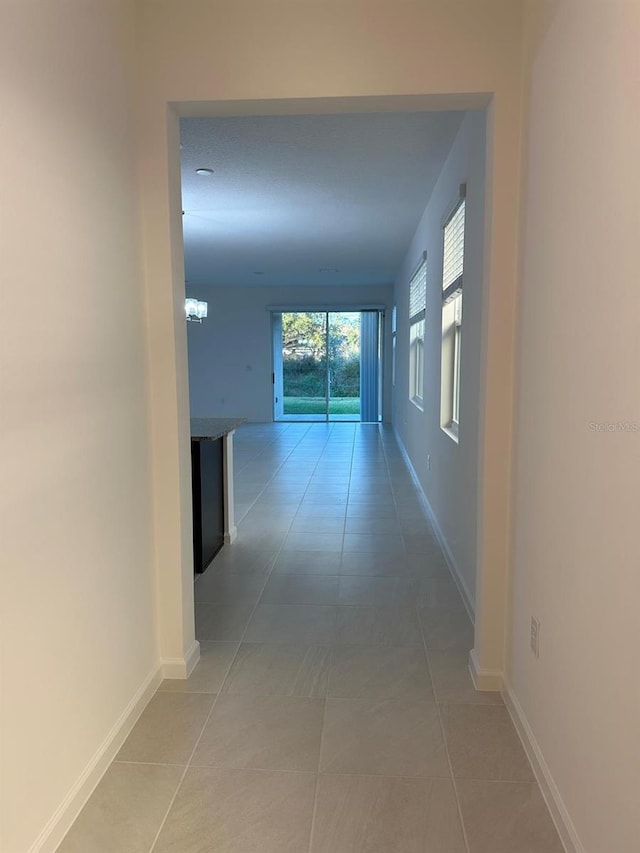 hallway featuring baseboards and light tile patterned flooring