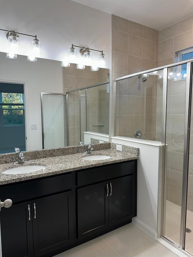 bathroom with a stall shower, tile patterned floors, a sink, and double vanity