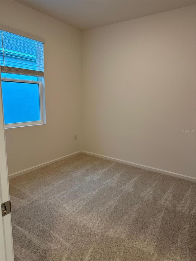 spare room featuring carpet and baseboards