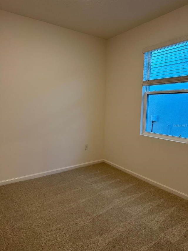 carpeted empty room featuring baseboards