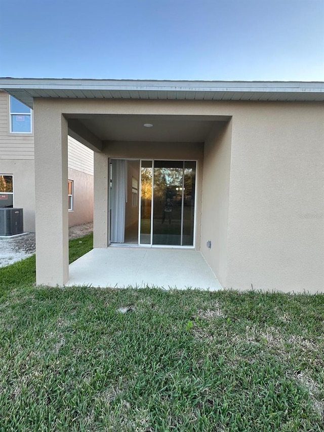 back of property featuring central air condition unit, a lawn, a patio, and stucco siding