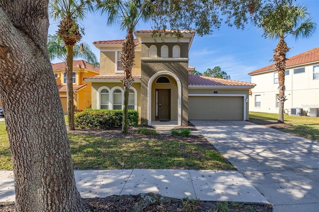 mediterranean / spanish house featuring an attached garage, central AC, a tile roof, concrete driveway, and stucco siding