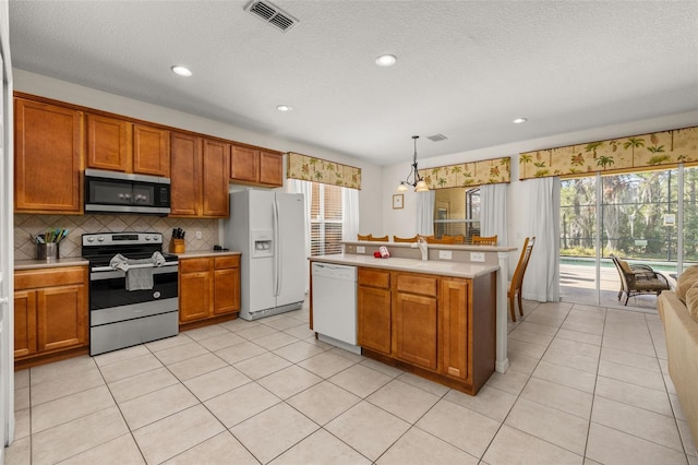 113 Tiger Lily Ct, Davenport, FL 33837 - kitchen with appliances with stainless steel finishes, light countertops, brown cabinets, light tile patterned flooring, and recessed lighting
