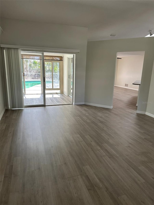 spare room featuring baseboards, visible vents, and dark wood-style flooring