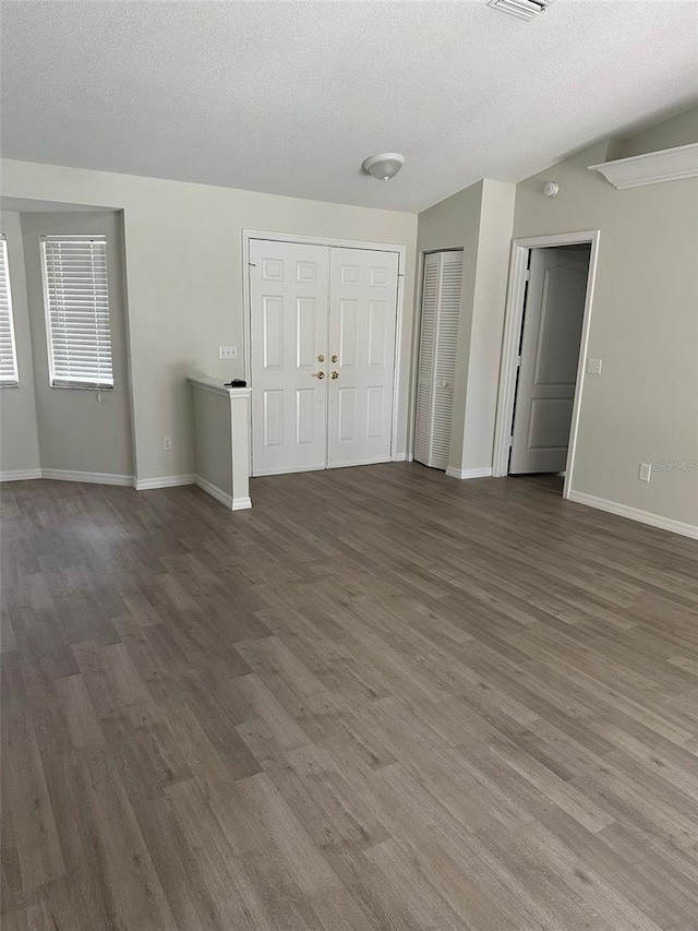 interior space featuring dark wood-style floors, a textured ceiling, and baseboards