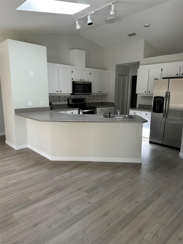 kitchen featuring visible vents, a peninsula, stainless steel appliances, white cabinetry, and a sink