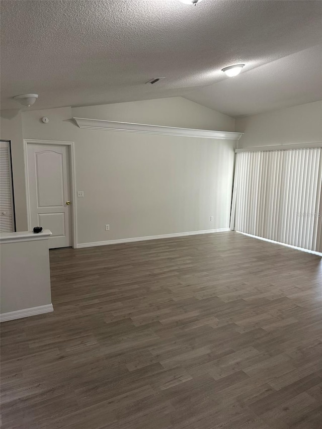 empty room with lofted ceiling, dark wood finished floors, and a textured ceiling