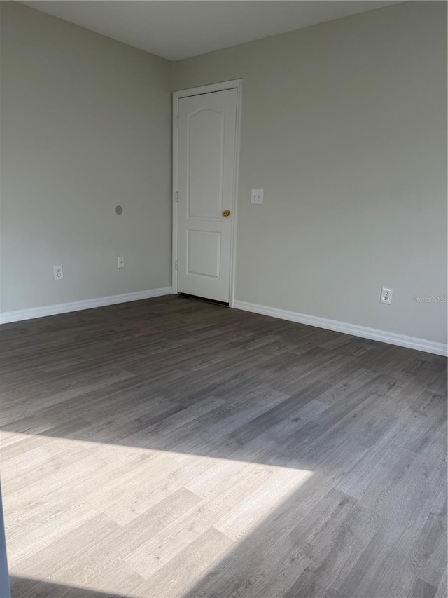 spare room with dark wood-type flooring and baseboards