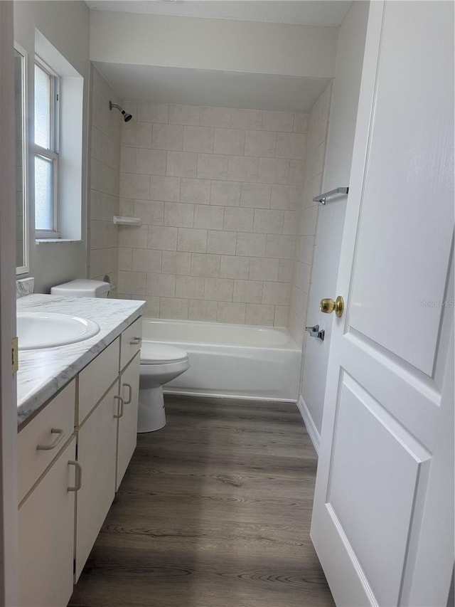 bathroom with toilet, washtub / shower combination, wood finished floors, and vanity